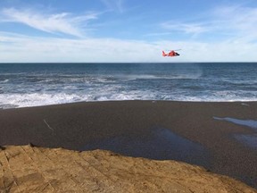 In this photo provided by the Oregon State Police taken Sunday, Jan. 15, 2017, a U.S. Coast Guard helicopter searches a beach about two miles north of Cape Blanco, Oregon, where a father and his young son were swept out to sea Sunday as they walked near the surf. (Oregon State Police via AP)