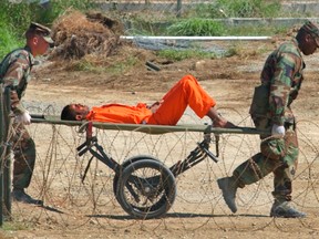 In this Feb. 2, 2002 file photo, a detainee from Afghanistan is carried on a stretcher before being interrogated by military officials at the detention facility Camp X-Ray on Guantanamo Bay U.S. Naval Base in Cuba. The White House said Tuesday, Jan. 17, 2017 that the detention center will still be open when President Barack Obama leaves office, conceding that a core campaign promise will go unfulfilled. (AP Photo/Lynne Sladky, File)