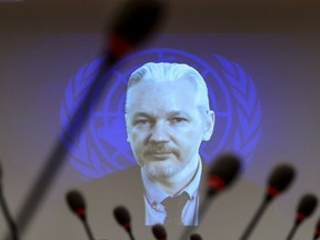 Picture taken on March 23, 2015, shows WikiLeaks founder Julian Assange on a screen speaking via web cast from the Ecuadorian Embassy in London during an event on the sideline of the United Nations (UN) Human Rights Council session in Geneva. (AFP PHOTO/FABRICE COFFRINI)