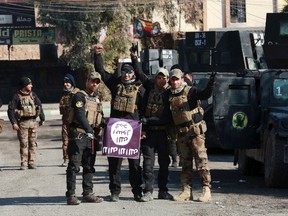 Iraq's special forces troops celebrate as they hold a flag of the Islamic State group they captured after regaining control of Andalus neighborhood in the eastern side of Mosul, Iraq, Monday, Jan. 16, 2017. Iraqi troops have begun to push Islamic State militants out of the last remaining neighborhoods between government-held territory in the eastern Mosul and the Tigris river which divides the city. (AP Photo/ Khalid Mohammed)