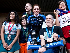 Clara Hughes, centre, poses with people from the crowd who are wearing some of her Olympic medals during the Edmonton leg of Clara's Big Ride at Mill Woods Park in Edmonton, Alta., on Sunday, June 1, 2014. Olympian Clara Hughes went on a 110 km tour through every province and territory to grow awareness for mental health.