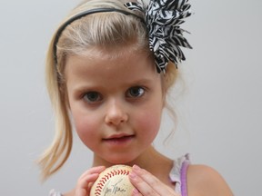Georgia Kate Riggs, the five-year-old granddaughter of former Citizen writer Dan Turner, holds a baseball signed by Montreal Expos Hall of Famer Tim Raines. (Jean Levac, Postmedia Network)
