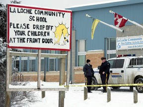 Members of the RCMP stand outside the La Loche Community School in La Loche, Sask. Monday, Jan. 25, 2016. (THE CANADIAN PRESS/Jonathan Hayward)