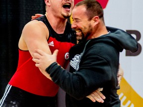 Boady Santavy, left, embraces his father and coach, Dalas, after breaking his all-time clean and jerk record at the junior national championships this past Saturday in Brossard, Que. Boady completed 188 kilograms, one better than Dalas' mark set in 2005. (Handout)