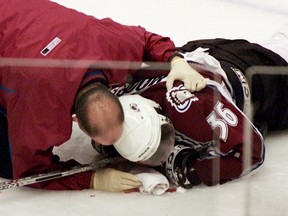 Avalanche forward Steve Moore is attended to by a team trainer after being injured against the Canucks in Vancouver on March 8, 2004. Moore never played another game in the NHL. (Chuck Stoody/The Canadian Press/Files)