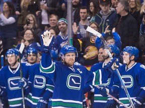 Canucks captain Henrik Sedin waves as he receives a standing ovation from his teammates on the bench and the crowd after scoring a goal against the Panthers to record his 1,000th career point during NHL action in Vancouver on Friday, Jan. 20, 2017. (Darryl Dyck/The Canadian Press)
