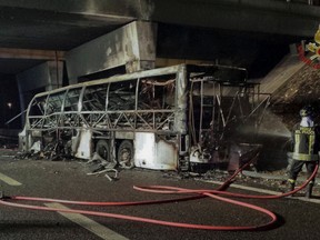 A firefighter sprays water on the burned hulk of a bus that crashed and burst into flames near Verona, northern Italy, Saturday, Jan. 21, 2017. (Italian Firefighters/ANSA via AP)