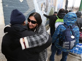 Althea Guiboche, also known as the Bannock Lady, hugs people in line for bannock and other free food at the corner of Dufferin Avenue and Main Street in Winnipeg on Sunday, Jan. 22, 2017, as the Got Bannock event celebrated four years of feeding the needy. (Kevin King/Winnipeg Sun/Postmedia Network)