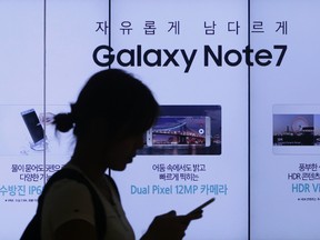 In this Sept. 2, 2016, file photo, a woman walks by an advertisement of Samsung Electronics' Galaxy Note 7 smartphone at the company's showroom in Seoul, South Korea. Samsung Electronics said Friday, Jan. 20, 2017 it will announce the reason why its Galaxy Note 7 smartphones overheated and caught fire on Jan. 23. (AP Photo/Ahn Young-joon, File)