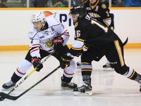 Owen Sound Attack's Nick Suzuki tries to get a shot off under pressure by the Sarnia Sting's Jordan Ernst during Ontario Hockey League action earlier this season.