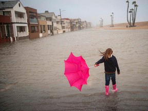 Isabella Busse , 6, walks through floodwater near the Seal Beach Pier during a storm in Seal Beach, Calif., Sunday, Jan. 22, 2017. The heavy downpour on Sunday drenched Orange County in one of the heaviest storms of the year. Fast-moving floodwaters swept through California mountain communities and residents fled homes below hillsides scarred by wildfires as the third in the latest series of storms brought a deluge Sunday and warnings about damaging mudslides. (Ana Venegas/The Orange County Register via AP)