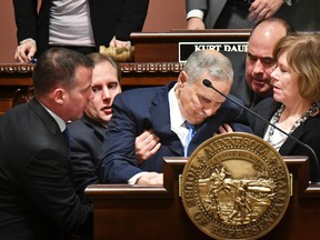 Minnesota Lt.-Gov. Tina Smith, right, and Secretary of State Steve Simon, left, help Minnesota Gov. Mark Dayton after he collapsed during his State of the State address in St. Paul, Minn., Monday, Jan. 23, 2017. House Speaker Kurt Daudt said minutes after the incident that Dayton was "up and about" and that the governor would be OK. (Glen Stubbe/Star Tribune via AP)