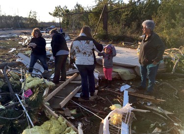 Bonnie Collier, right, and her two granddaughters, daughter and daughter-in-law pick through the wreckage of her mobile home trying to find clothes and family photos on Monday, Jan. 23, 2017, near Cecil, Ga. (AP Photo/Brendan Farrington)