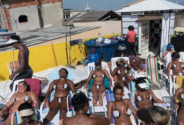 In this Jan. 15, 2017 photo, women in search of crisp tan lines wear bikinis created from black electrical tape at the Erika Bronze rooftop salon in the suburb of Realengo in Rio de Janeiro, Brazil. Today, Martins' rooftop fits 30 women and is at full capacity seven days a week, as long as the sun is out. Her Facebook page has 68,000 followers. (AP Photo/Renata Brito)