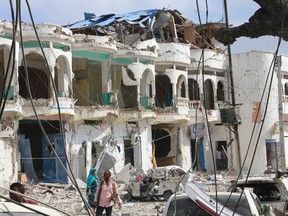Somalis walk near a hotel heavily damaged by a car bomb blast in Mogadishu, Somalia, Wednesday, Jan. 25, 2017. Gunmen from Somalia's violent Islamic extremist rebels fought their way into a hotel in the Somali capital after a suicide car bomb exploded at its gates, a police officer said Wednesday. (AP Photo/Farah Abdi Warsameh)