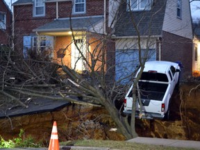 A pickup truck dangles over the edge of a sinkhole that swallowed parts of two residential yards Wednesday morning, Jan. 25, 2017, in the Philadelphia suburb of Glenside, Pa. Officials in Cheltenham Township say the hole, which appears to be about 20 feet deep, opened up about 4 a.m. Wednesday. (Emily Casher Loomis via AP)