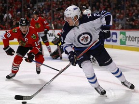 Patrik Laine of the Winnipeg Jets looks to pass as Jonathan Toews of the Chicago Blackhawks closes in during a game last month. (FILE PHOTO)