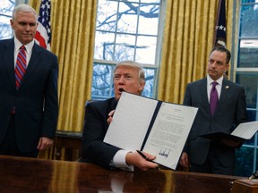 In this Jan. 23, 2017, photo, Vice President Mike Pence, left, and White House Chief of Staff Reince Priebus watch as President Donald Trump shows off an executive order to withdraw the U.S. from the 12-nation Trans-Pacific Partnership trade pact agreed to under the Obama administration in the Oval Office of the White House in Washington. Trump’s "peace through strength" could mean more U.S. military power in Asia, reassuring allies about America’s resolve to counter China. That is, if they’re still looking to Washington for reassurance. Trump called his speedy withdrawal from the Trans-Pacific Partnership a victory for American workers hurt by multilateral trade pacts. (AP Photo/Evan Vucci)