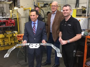 Ontario Economic Development Minister Brad Duguid displays a freshly-stamped part at Armo Tool while Middlesex Centre Mayor Al Edmondson and Armo Tool president Ben Whitney. (HANK DANISZEWSKI, The London Free Press)