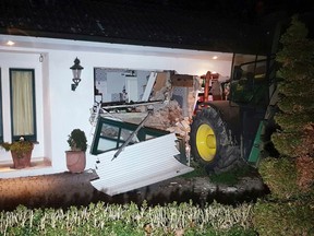 A tractor stands in front of a damaged house after it broke through the wall in Buende, north-western Germany, Thursday, Jan. 26, 2017. Unknown intruders steered the tractor into the house and broke through the wall in order to steal a safe. The residents were not injured. (Nord-West-Media TV/dpa via AP)