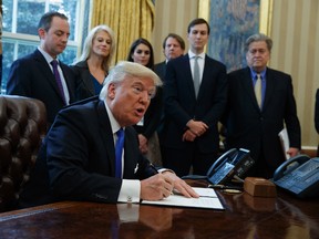 President Donald Trump signs an executive order on the Keystone XL pipeline, Tuesday, Jan. 24, 2017, in the Oval Office of the White House in Washington. (AP Photo/Evan Vucci)