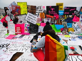 In this Saturday, Jan. 21, 2017 photo, protesters build a wall of signs outside the White House for the Women's March on Washington during the first full day of Donald Trump's presidency. Signs from the women's marches around the world are being saved as cultural treasures by museums, libraries and colleges. (AP Photo/John Minchillo)