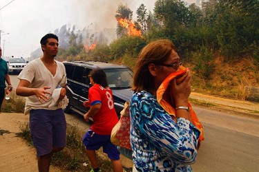 People react to the advancement of a forest fire in Hualañe, a community in Concepcion, Chile, Wednesday, Jan. 25, 2017. The worst forest fires in Chile's history were uncontrolled on Wednesday, killing a firefighter and two policemen caught in the flames as they tried to help families in rural communities, authorities said. (Alejandro Zoñez/Aton via AP)