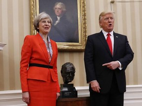 President Donald Trump points to the bust of British Prime Minister Winston Churchill as he poses for photographs with British Prime Minister Theresa May in the Oval Office of the White House in Washington, Friday, Jan. 27, 2017. (AP Photo/Pablo Martinez Monsivais)