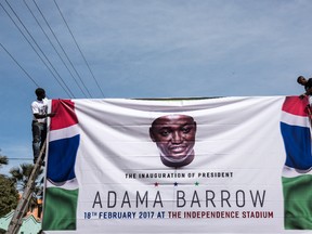 Men hang a banner for the inauguration ceremony of Gambian President Adama Barrow prior to his return on January 26, 2017 in Banjul, The Gambia. Barrow had been staying in Senegal after authoritarian ex-president Yahya Jammeh refused to step down following December election results. (Photo by Andrew Renneisen/Getty Images)
