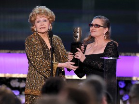 In this Jan. 25, 2015, file photo, Carrie Fisher, right, presents her mother Debbie Reynolds with the Screen Actors Guild life achievement award at the 21st annual Screen Actors Guild Awards in Los Angeles. (Vince Bucci/Invision/AP, File)
