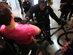 A Seattle police officer pushes the last group of protesters out of the airport terminal after giving a final dispersal order around 2 a.m. Sunday, Jan. 29, 2017 at Seattle-Tacoma International Airport. (Genna Martin/seattlepi.com via AP)