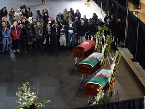 Mourners look on as the caskets of three of the victims of the Quebec City mosque shooting are lined up before a funeral at the Maurice Richard Arena in Montreal, Thursday, February 2, 2017. THE CANADIAN PRESS/Paul Chiasson