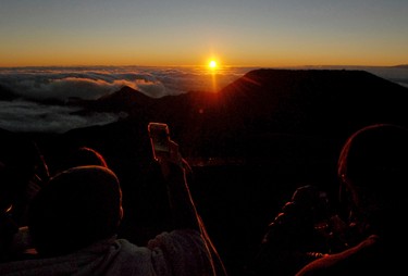 People watch as the sun rises in front of the summit of Haleakala volcano in Haleakala National Park on Hawaii's island of Maui, Sunday, Jan. 22, 2017. Reservations can be made up to two months in advance at the website recreation.gov. (AP Photo/Caleb Jones)