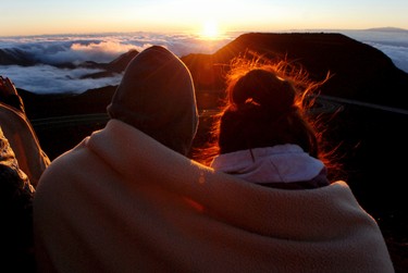 A couple watches as the sun rises in front of the summit of Haleakala volcano in Haleakala National Park on Hawaii's island of Maui, Sunday, Jan. 22, 2017. Sunrise viewing has long been popular at Haleakala, one of the main attractions at Haleakala National Park despite morning temperatures that often dip into the 30s. (AP Photo/Caleb Jones)