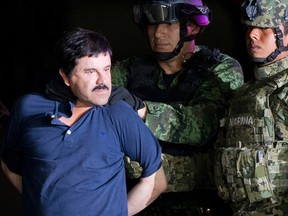 In this Jan. 8, 2016 file photo, a handcuffed Joaquin "El Chapo" Guzman is made to face the press as he is escorted to a helicopter by Mexican soldiers and marines at a federal hangar in Mexico City. Guzman is scheduled to appear in person in a federal court in New York. A judge initially ruled that Guzman would appear in court by video on Friday, Feb. 3, rather than have marshals escort him to and from a high-security Manhattan jail cell. The order was changed after his lawyers asked the judge to reconsider. (AP Photo/Eduardo Verdugo, File)