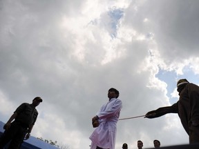 A sharia policeman canes a man for drinking alcohol and breaking Islamic law, during a public punishment in Banda Aceh on March 1, 2016. Iran's supreme court has ruled that a jilted woman who blinded a love rival with acid must lose one eye as punishment. (GETTY IMAGES)