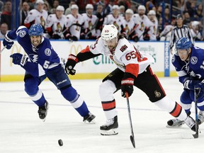 Senators defenceman Erik Karlsson races to the puck ahead of Tampa Bay Lightning’s Jason Garrison on Thursday night. (AP)