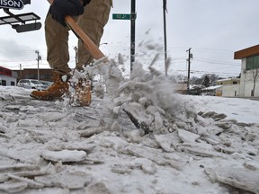 Scrapping compacted snow and ice on sidewalk along 107 Ave. in Edmonton, Saturday, February 4, 2017. Ed Kaiser/Postmedia