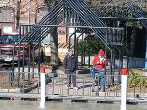 A pair of men watch the water rise along the banks of the Sydenham River in downtown Wallaceburg in this file photo. (David Gough/Postmedia Network)