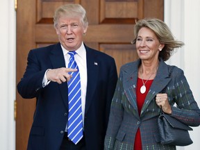 In this Nov. 19, 2016 file photo, President-elect Donald Trump, left, and Betsy DeVos, right, pose for photographs at Trump National Golf Club Bedminster's clubhouse in Bedminster, N.J. Republican Ohio Gov. John Kasich wrote a Jan. 24, 2017, letter urging confirmation of DeVos, Trump's education secretary nominee, without mentioning the significant unpaid fine owed to Ohio by a now-defunct political action committee she controlled. (AP Photo/Carolyn Kaster, File)