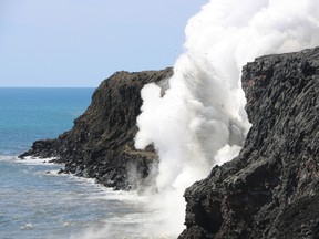 In this Feb. 2, 2017 photo provided by the U.S. Geological Survey, debris flies into the air after a section of sea cliff collapses into the ocean above a "firehose" lava stream in Hawaii Volcanoes National Park on Hawaii's Big Island. The section of land collapsed as a tour boat full of spectators and USGS geologists watched on Thursday afternoon. The collapse stopped the heavy stream of lava that had been arching out from near the top of the cliffs for weeks. The lava stream, dubbed a "firehose" flow because it shoots lava outward from the source like water from a hose, had recently increased in intensity. (USGS via AP)
