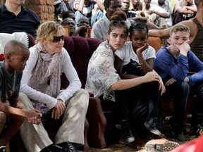 This file photo taken on April 2, 2013 shows US Pop Star Madonna (2nd L) sitting with her biological and adopted children (L to R) David Banda, Lourdes, Mercy James, and Rocco at Mkoko Primary School, one of the schools Madonna's Raising Malawi organization has built jointly with US organization BuildOn, during a visit in the region of Kasungu, central Malawi.
A court in Malawi on February 7, 2017 approved Madonna's request to adopt two four-year-old twin girls, adding to the two other children that the US pop superstar adopted previously from the country. / AFP PHOTO / AMOS GUMULIRAAMOS GUMULIRA/AFP/Getty Images