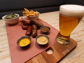 Chicken and blueberry (foreground), Merguez lamb and beef (centre) and the OTTO Dog sausages are seen on a platter with french fries, a glass of beer and a house salad at Otto restaurant at 11405 95 Street in Edmonton, Alberta on Monday, January 9, 2017. Ian Kucerak / Postmedia