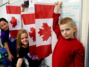 Students, Austin Law, from front, Meghan MacVar and Sarah Song hold flags at Bath Public School on Tuesday. (Ian MacAlpine/The Whig-Standard)