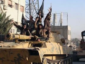 In this undated file image posted by the Raqqa Media Center in Islamic State group-held territory, on Monday, June 30, 2014, which has been verified and is consistent with other AP reporting, fighters from the Islamic State group ride tanks during a parade in Raqqa, Syria. (AP Photo/Raqqa Media Center, File)