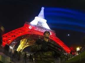 A French soldier enforcing the Vigipirate plan, France's national security alert system, is pictured on November 18, 2015 in Paris in front of the Eiffel Tower, which is illuminated with the colors of the French national flag in tribute to the victims of the November 13 Paris terror attacks in which some 129 people were killed. AFP PHOTO / JOEL SAGET (Photo credit should read JOEL SAGET/AFP/Getty Images)