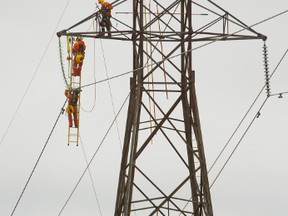 Workers from Hydro One have a good view as they are work high on a transmission tower at Highway 401 and 74 east of London, Ont. on Wednesday February 8, 2017. The workers are replacing old insulators with new versions. (MIKE HENSEN, The London Free Press)