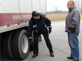 Chatham-Kent OPP Rob Enzlin talks to a truck driver who attended a wheel separation clinic held near Tilbury, Ont. in December 2015. ELLWOOD SHREVE / POSTMEDIA