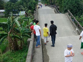 Residents look at the collapsed portion of a bridge in Surigao hours after a powerful earthquake rocked Surigao del Norte province Saturday, Feb.11, 2017 in southern Philippines. The late Friday quake with a magnitude of 6.5 roused residents from sleep in the province, sending hundreds to flee their homes. (AP Photo)