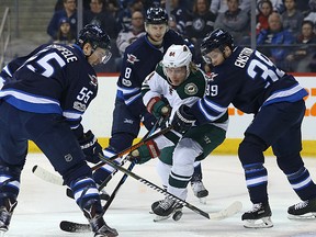 Minnesota Wild forward Mikael Granlund (centre) chases a puck as Winnipeg Jets centre Mark Scheifele and defence men Jacob Trouba and Toby Enstrom (from left) defend in Winnipeg on Tues., Feb. 7, 2017. Kevin King/Winnipeg Sun/Postmedia Network
